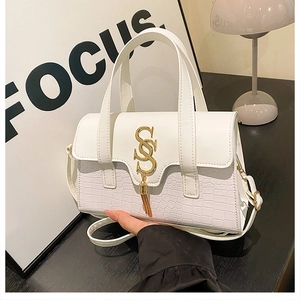 Detail of white leather handbag featuring gold SS hardware and stylish tassel pendant