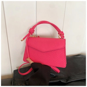 Détail du sac à main rouge rose avec texture tissée, anneau doré et poignée nouée