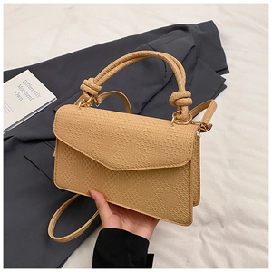 Détail d'un sac à main beige tissé avec poignée nouée unique et bandoulière élégante