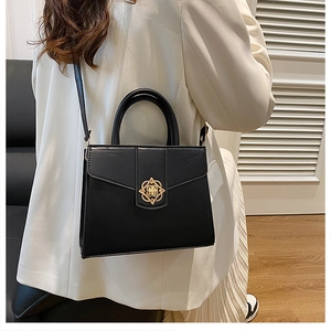 Minimalist black leather square handbag with golden woven buckle shown on model