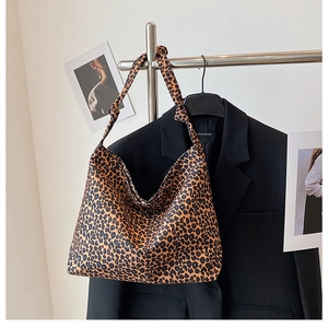 Detail view of large leopard print tote bag with stylish knot handle on a hanger