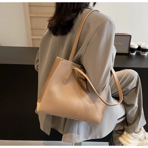 Detail of light brown leather tote bag with FASHION tag worn over shoulder