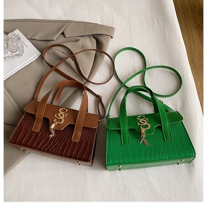 Detail of luxury crocodile texture handbags in brown and green with gold metal hardware