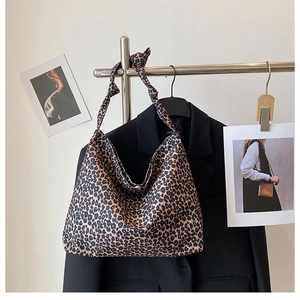 Detail view of leopard print tote bag hanging on a rack with knotted shoulder strap