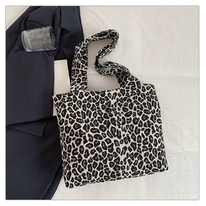 Detail of leopard print canvas tote bag with wide shoulder strap on white fabric