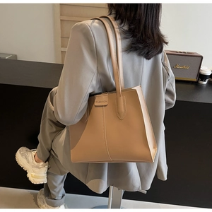 Detail of light brown PU leather tote bag with FASHION patch and minimalist shoulder strap