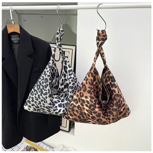 Detail of leopard print knot handbags in brown and grey canvas hung on a display rack