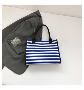 Close-up of blue and white striped canvas tote bag with black strap and metal snap button