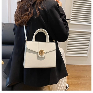 Rear view of cream leather tote bag featuring golden floral clasp and adjustable strap