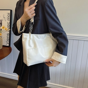 Grand sac cabas blanc minimaliste avec bandoulière chaîne porté par un mannequin en intérieur