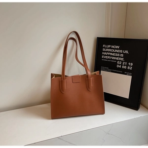 Detail view of caramel brown leather tote bag with elegant stitching and long shoulder strap