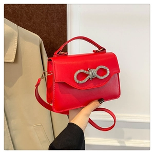 Detail of red PU leather handbag featuring a sparkling silver rhinestone bow clasp