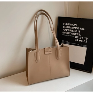 Close-up of minimalist beige tote bag showing matte leather texture and FASHION embossed label