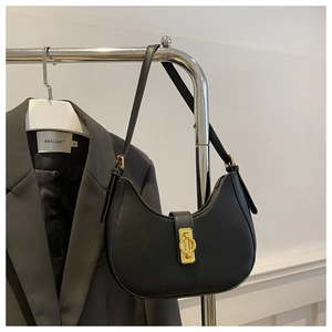 Détail du sac hobo croissant noir mat avec boucle dorée sur une veste de costume grise