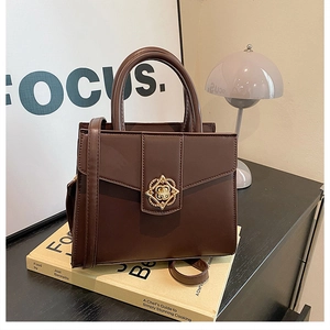 Close-up of the golden flower-shaped metal lock on a brown synthetic leather handbag