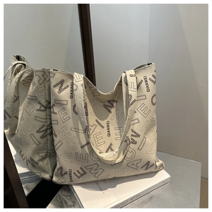Detailed macro view of the textured lychee grain leather and letter print on tote bag