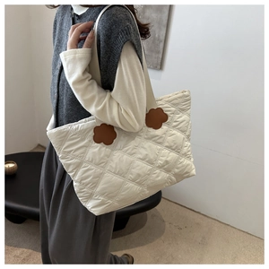 Detailed view of cream quilted tote bag featuring brown floral leather strap accents