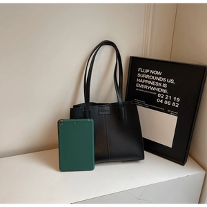 Detail of minimalist black PU leather tote bag with magnetic 'FASHION' buckle closure