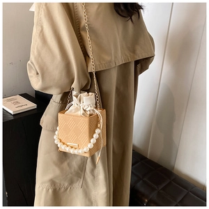 Dettaglio della borsa a secchiello beige con manico di perle e fodera in seta