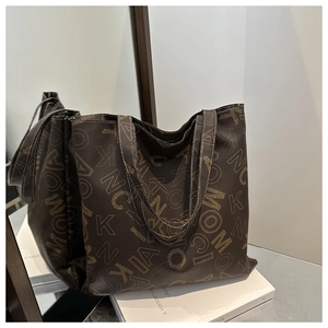 Macro detail of the brown leather tote bag showing MOCIA letter prints and texture