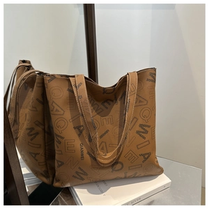Detail of vintage brown tote bag with letter print and smooth faux leather texture