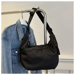 Close-up of black nylon crescent bag with adjustable wide strap and decorative zipper pull