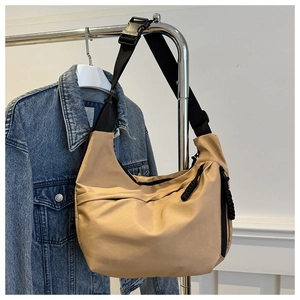 Detail of khaki nylon crescent bag featuring wide black strap and quick-release buckle