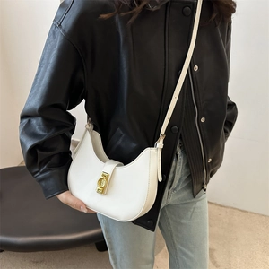 Sac hobo blanc chic avec boucle dorée porté par un mannequin en veste de cuir noir