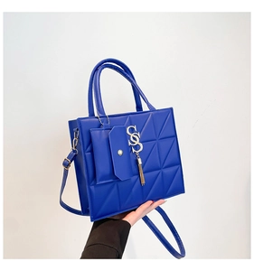 Detail of royal blue quilted leather handbag with gold SSS charm and tassel fringe