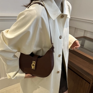Sac hobo marron foncé en forme de croissant avec boucle dorée vintage porté sous le bras