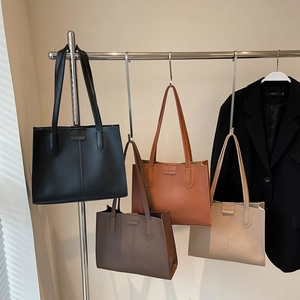 Minimalist faux leather tote bags in black, caramel, coffee, and beige on metal display