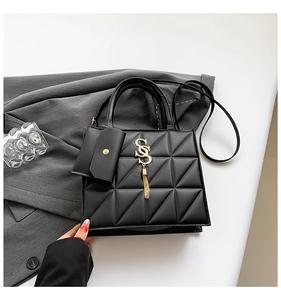 Detail of black quilted leather handbag with gold SS logo and tassel keychain accessory