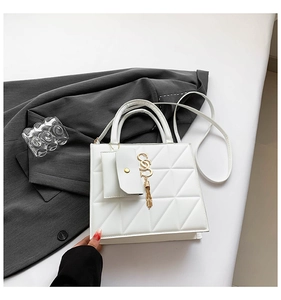 Detail of white quilted crossbody bag with golden letter tassel and detachable strap