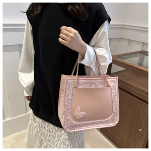 Detailed shot of pink faux fur and leather tote bag featuring an embroidered butterfly