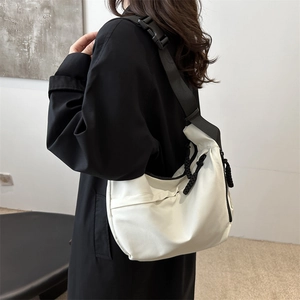 Large white nylon crossbody dumpling bag with adjustable black strap worn by a model