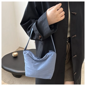 Detail of light blue hobo bag showing nylon texture and draped silhouette on a model