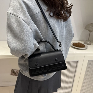 Chic black crossbody bag with woven texture detail and twin decorative buttons on the flap