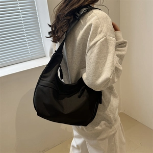 Minimalist black half-moon tote bag with adjustable wide strap for casual commuting