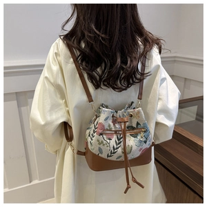 Detalle de bolso saco de tapiz floral con base de cuero marrón y cierre de cordón