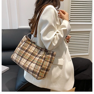 Close-up of vintage brown plaid felt tote bag with leather straps and silver metal rings