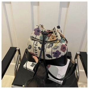 Detalle de bordado floral en bolso saco de lona con base de cuero y cremallera dorada