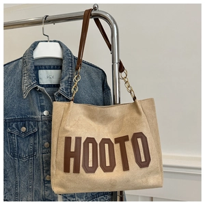 Dettaglio borsa tote in pelle scamosciata beige con scritte HOOTO e catena metallica