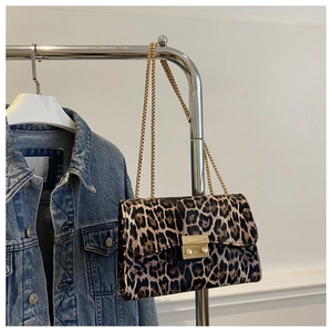Detail of leopard print crossbody bag with gold chain strap on a clothing rack