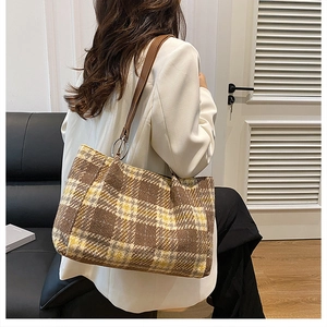 Brown plaid felt tote bag with leather straps worn by model in cozy indoor setting