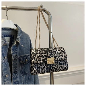 Detail view of leopard print texture and golden chain on a chic crossbody bag