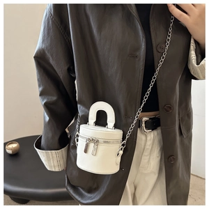 Mini borsa cilindrica bianca con tracolla a catena su giacca in pelle scura
