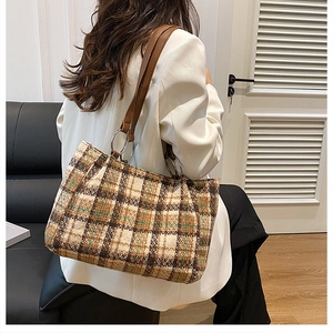 Detail of plaid tweed tote bag showing leather handles and large silver metal rings