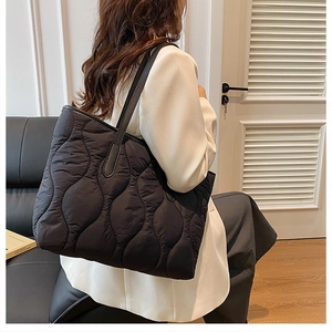 Moderna borsa tote nera trapuntata indossata da modella in un elegante interno