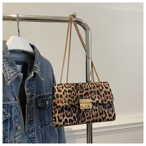 Detail of leopard print chain bag featuring a gold clasp and metal shoulder strap
