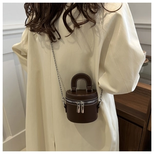 Dettaglio mini borsa cilindrica marrone scuro con cuciture bianche e catena in argento